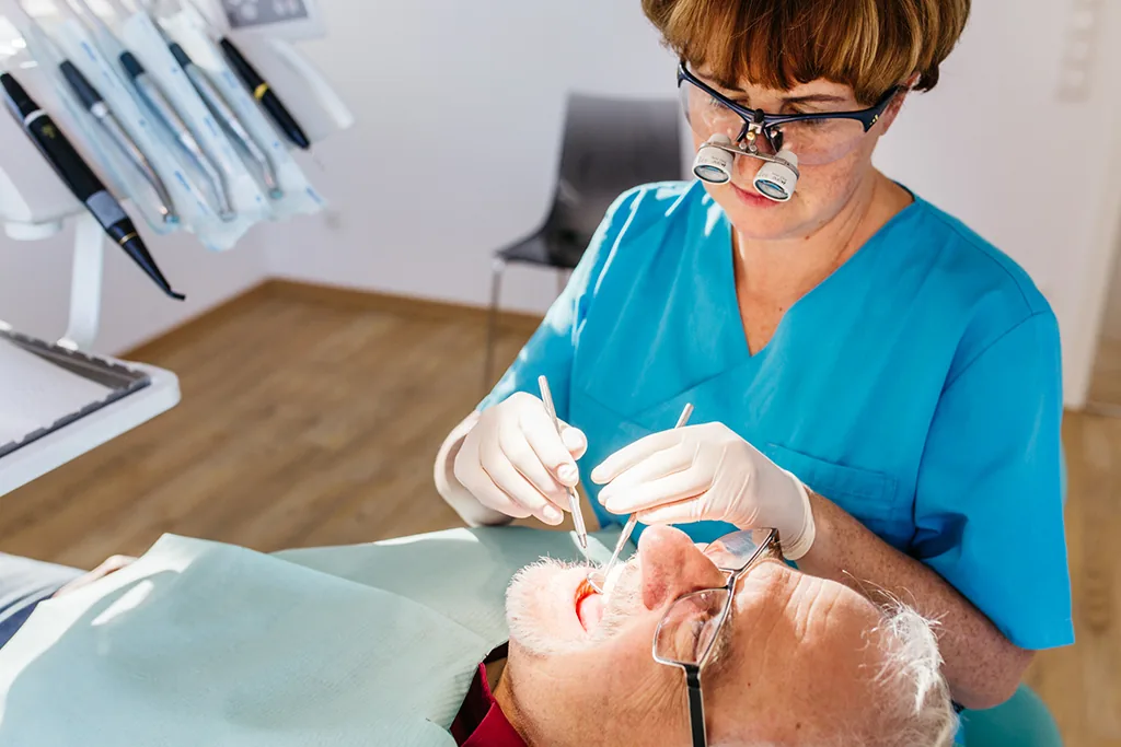 Zahnärztin bei der Behandlung, konzentrierte Arbeit mit Lupenbrille