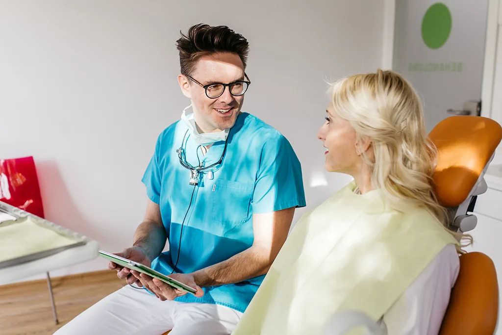 Zahnarzt im Gespräch mit einer Patientin auf dem Behandlungsstuhl