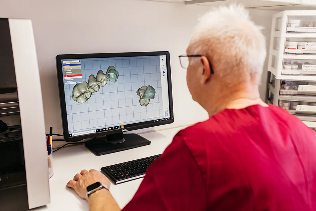 Zahntechniker konstruiert Kronen am Bildschirm mit CAD-Software