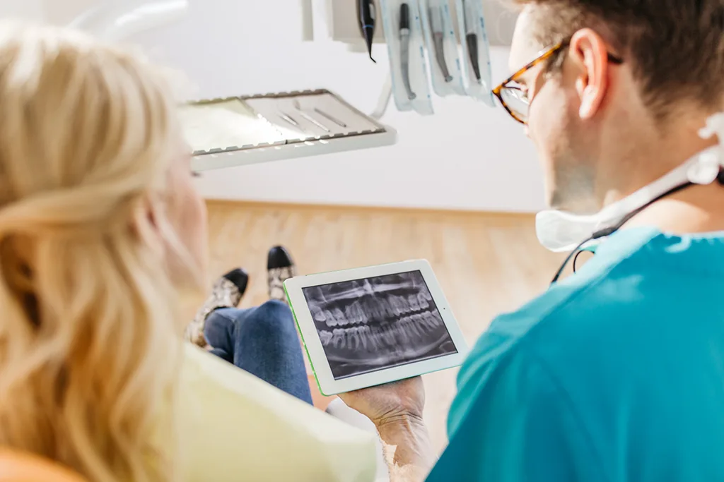 Zahnarzt zeigt einer Patientin ihr Röntgenbild auf dem Tablet