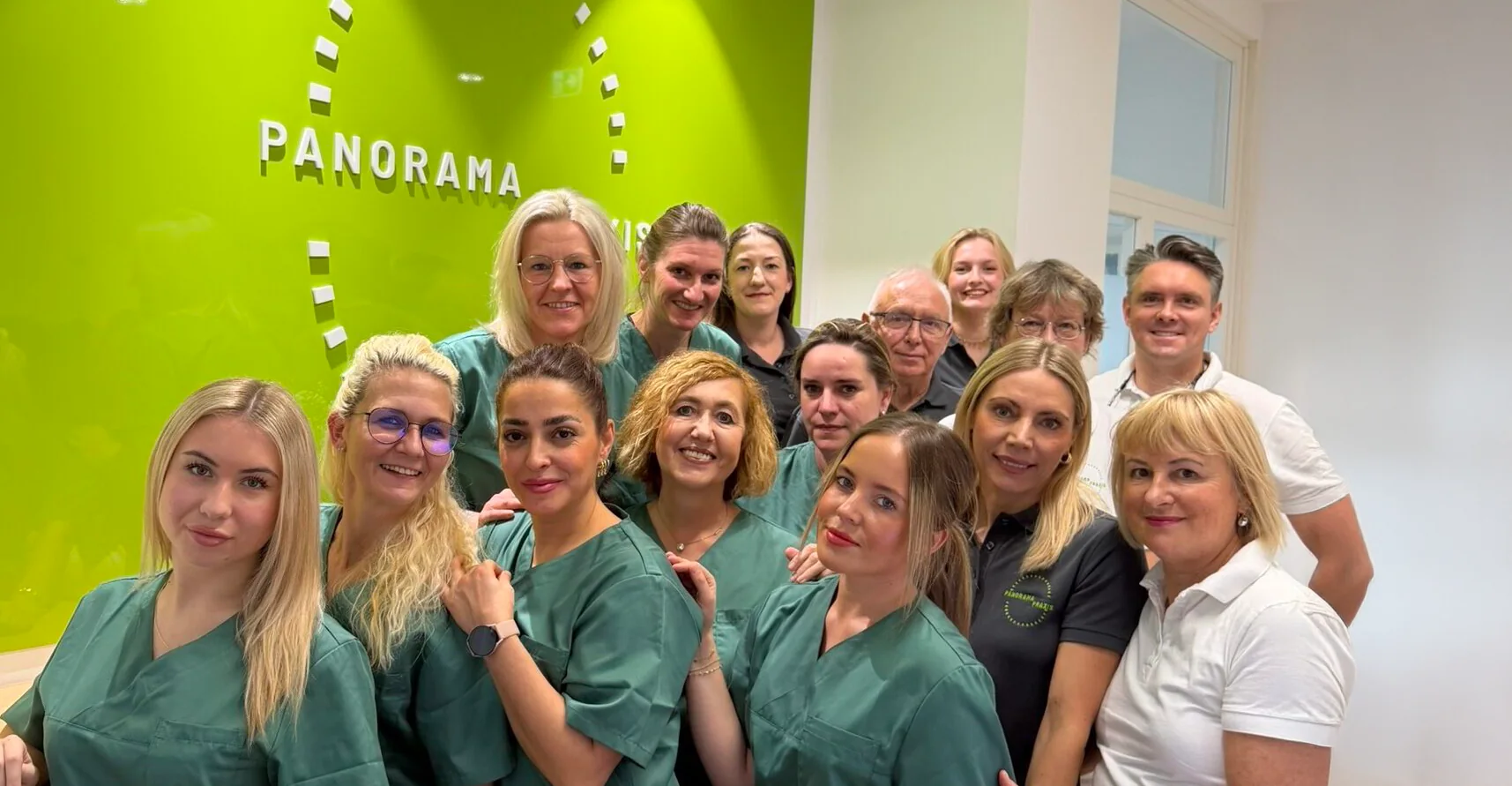 Das Team der Panorama Praxis vor der grünen Wand mit dem Praxislogo